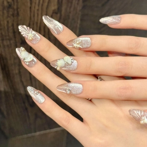 Detail of ocean-themed press-on nails with 3D pearls, shells, and starfish decorations