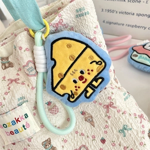 Close-up of a cartoon cheese plush pendant with fine embroidery and mint green braided cord