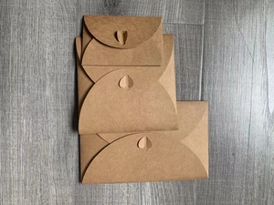 Detailed view of three stacked brown kraft envelopes with creative heart-shaped clasps