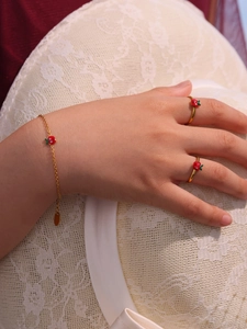 Dettaglio del set di gioielli mela dorata con bracciale e anelli su cappello di paglia