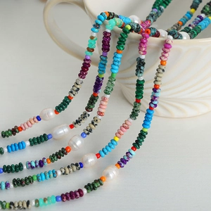 Ethnic style necklace with natural pearls and colorful gemstones on a white ceramic cup