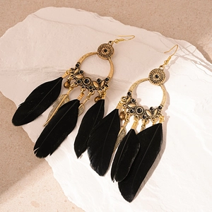 Detailed shot of Bohemian vintage gold earrings featuring black feather tassels on stone