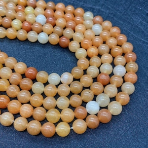Macro shot of 8mm natural red aventurine stone beads with smooth orange finish for jewelry