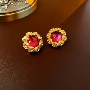 Macro detail of vintage gold earrings with red round stone and small white crystals
