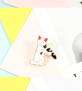 Close-up of a white cartoon cat enamel pin holding a yellow baguette bread over soft backgrounds