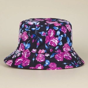 Detalle de cerca de un sombrero de pescador negro con rosas rosas y hojas azules