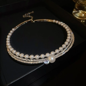 Detailed close-up of multi-layer pearl necklace with sparkling rhinestones and pendant