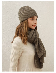 Detailaufnahme des dunkelbraunen Stricksets mit Mütze und Schal an einem Model