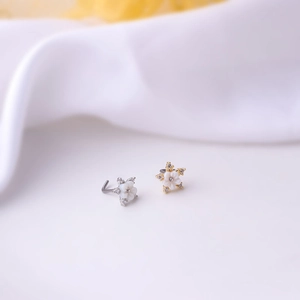 Macro detail of gold and silver flower nose studs with cubic zirconia petals