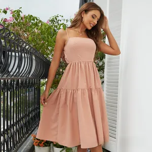 Detail of light pink backless maxi dress with delicate straps and tiered ruffled skirt