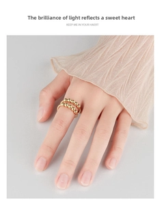Close-up of a rotatable gold bead anxiety ring worn on a finger for stress relief
