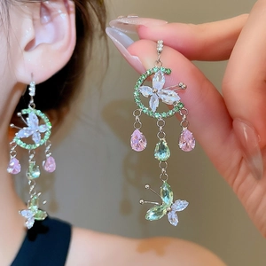 Macro shot of silver earrings with colorful zircon butterfly and moon drop pendants
