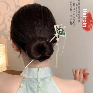 Detail of a vintage Chinese hair pin with green fan, pink flowers, and metal tassels