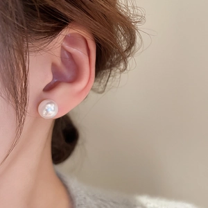 Close-up of minimalist white pearl earring worn on model for a classic look
