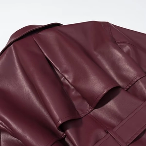Détail des pattes d'épaule et coutures sur un long trench-coat en cuir rouge foncé