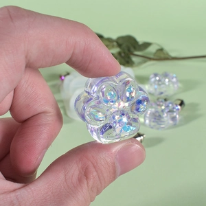 Macro detail of a translucent cat paw resin pendant with sparkling blue holographic glitters