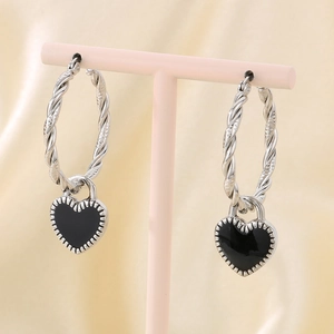 Vue détaillée de boucles d'oreilles torsadées en argent avec breloques cœur en émail noir