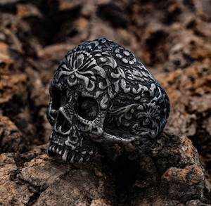 Macro shot of gothic pirate skull ring with baroque carvings on a rustic bark background
