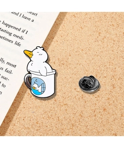 Detailed view of a cute white enamel duck pin holding a knife on a cork board and book