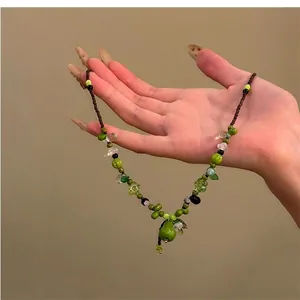 Détail du collier de perles avec pendentif Wu Lou vert et breloques de fleurs