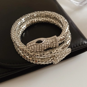 Macro detail of silver snake bracelet featuring sparkling rhinestones and black eye accents