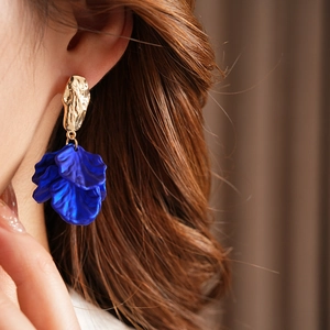 Close-up of vintage golden irregular metal earrings with deep blue petal tassel charms