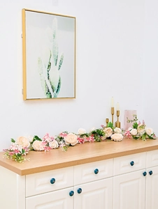Detailed view of champagne rose vine with pink blossoms on a white wooden cabinet