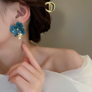 Close-up of blue flower earrings with bee pendant on model showing size and fit
