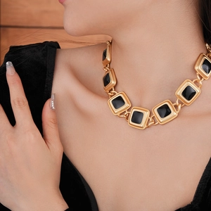 Detail of vintage gold necklace with black enamel square links worn on neck