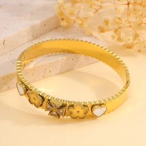 Detailed macro view of gold-plated titanium steel bracelet with heart and flower motifs