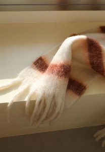Detailed close-up of thick beige and brown striped scarf with braided fringe tassels