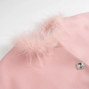 Détail du manteau en laine rose avec col en plumes et bouton strass carré