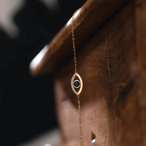 Macro shot of evil eye pendant with blue gemstone and white zircons on gold chain