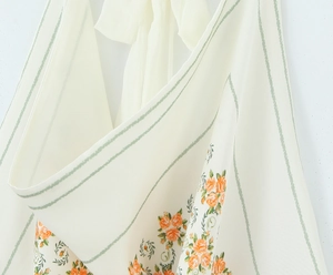 Macro detail of floral print chiffon fabric with orange flowers and green stripes