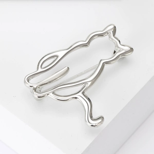 Detailed close-up of a silver hollowed-out cat outline brooch on white surface