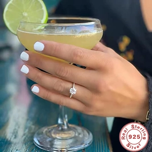 Close-up of a 925 sterling silver diamond ring on a hand holding a cocktail glass
