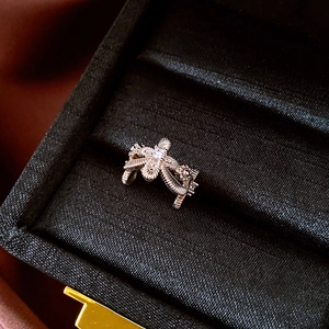 Macro-opname van een goudkleurige kruis-ear cuff met zirkoon in een luxe fluwelen doos