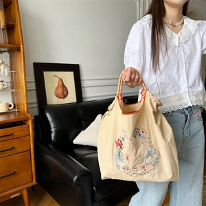 Gros plan d'une broderie florale sur un cabas en toile beige avec des anses tressées