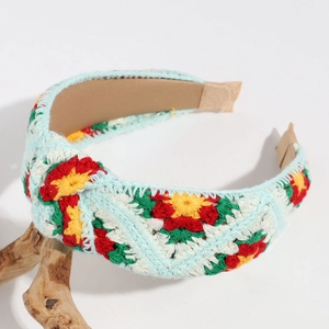 Detail of hand-knitted light blue headband with red floral embroidery and beige lining