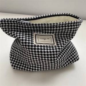 Detail of black and white houndstooth makeup bag with Pleasant Time woven label