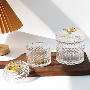 Set of two vintage glass storage jars with embossed diamond patterns and gold butterfly lids