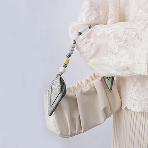Detail of cream white pleated cloud bag featuring an elegant silk scarf beaded handle strap