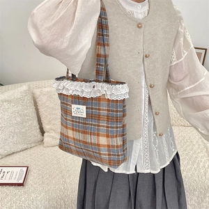 Detailed view of plaid wool tote bag with white lace trim and vintage cloth label