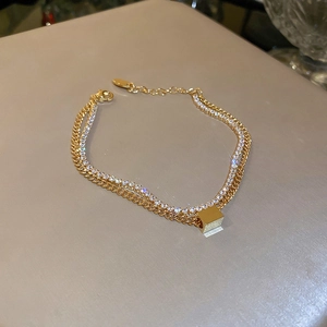 Detailed close-up of double-layer gold-plated bracelet with cubic zirconia and square pendant