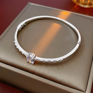 Detail of silver oval bracelet featuring a central round stone and side baguette zircons
