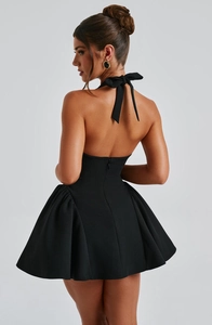Detail view of the elegant bow tie on the back of a black halter neck mini dress