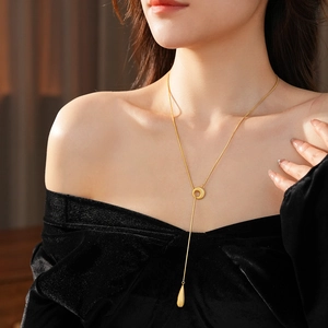 Close-up of gold-plated waterdrop pendant and ring clasp on a minimalist Y-necklace