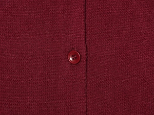 Détail macro du cardigan en maille rouge foncé avec texture dense et bouton assorti