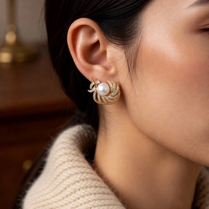 Close-up of elegant 18k gold pearl earrings with shimmering diamond-set feather wings