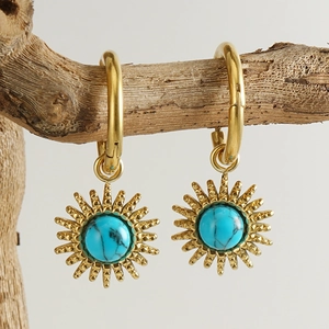 Bohemian gold sunburst earrings with turquoise stone hanging on a natural branch